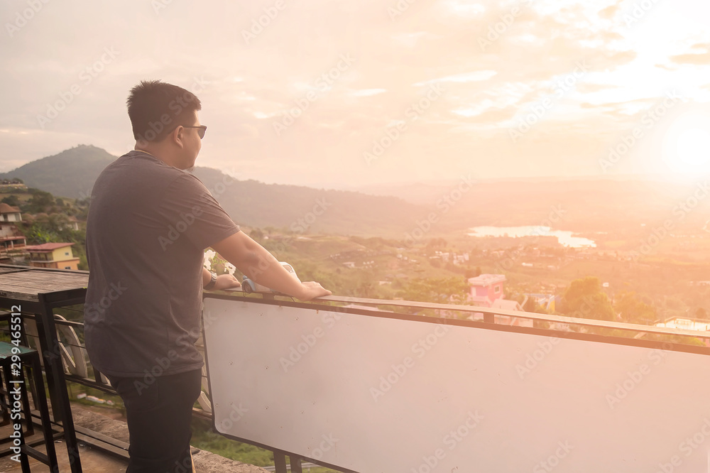 Asian man is standing on the balcony to see the beautiful sunset at Petchabun provice , Thailand.