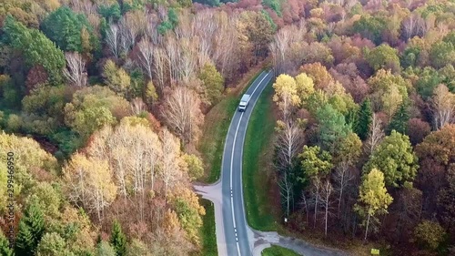 Aerial Shot of a Truck Travelling On Road In Colorful Autumn Forest. Scenic Country Road in Autumn Forest. photo