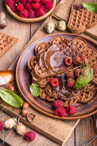 Belgium waffles heart with chocolate sauce raspberries on wood background.