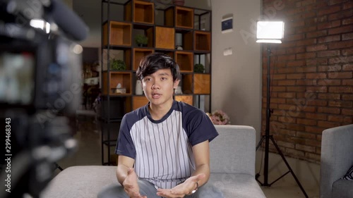 Asian young man blogger recording vlog talking to camera when work at home photo