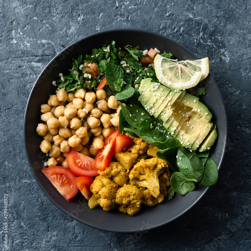 Buddha bowl Vegetarian healthy balanced food Aloo-gobi, chickpeas, tomato, avocado, tabule salad and spinach photo