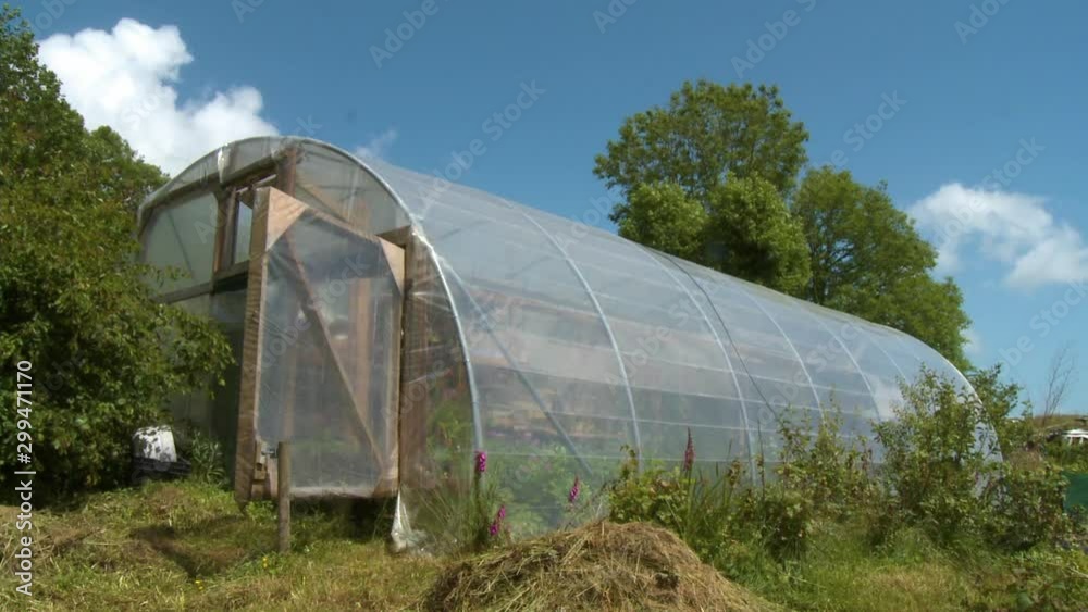 Wide low angle shot of the outside of a green house made of clear plastic over a wooden frame Wide low angle shot of the outside of a green house made of clear plastic over a wooden frame