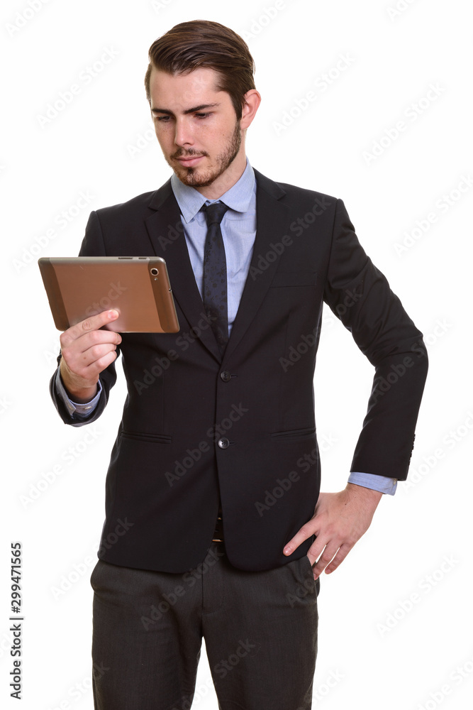 Portrait of young handsome bearded businessman in suit using digital tablet Portrait of young handsome bearded businessman in suit using digital tablet