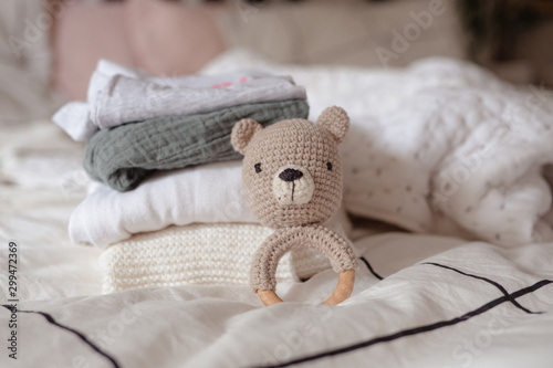 baby clothes with diapers are stacked with a pacifier and a toy bear