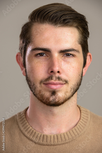 Face of young handsome bearded man looking at camera