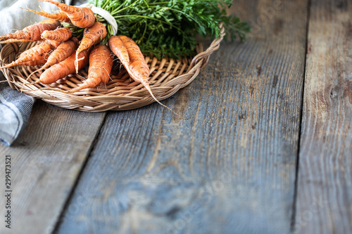 Organic carrots on a wicker tray, on a wooden dark background. Rustic natural style. copy space.