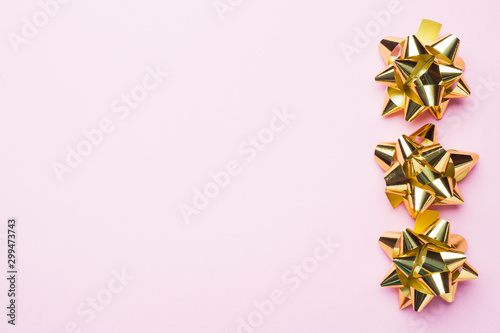 Gold Christmas bows on pink background. Gift concept greetings for holidays birthday Wedding New year Christmas mother's Day. Copy space.