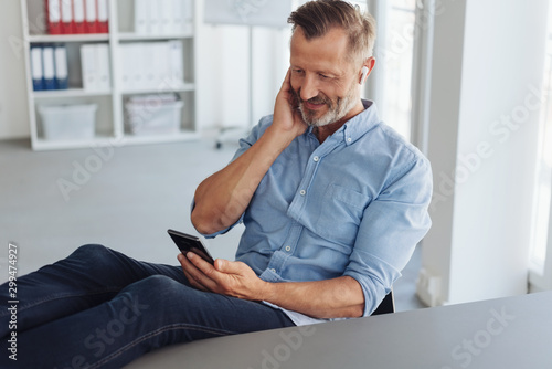 Canvas Print Businessman listening to audio on ear buds