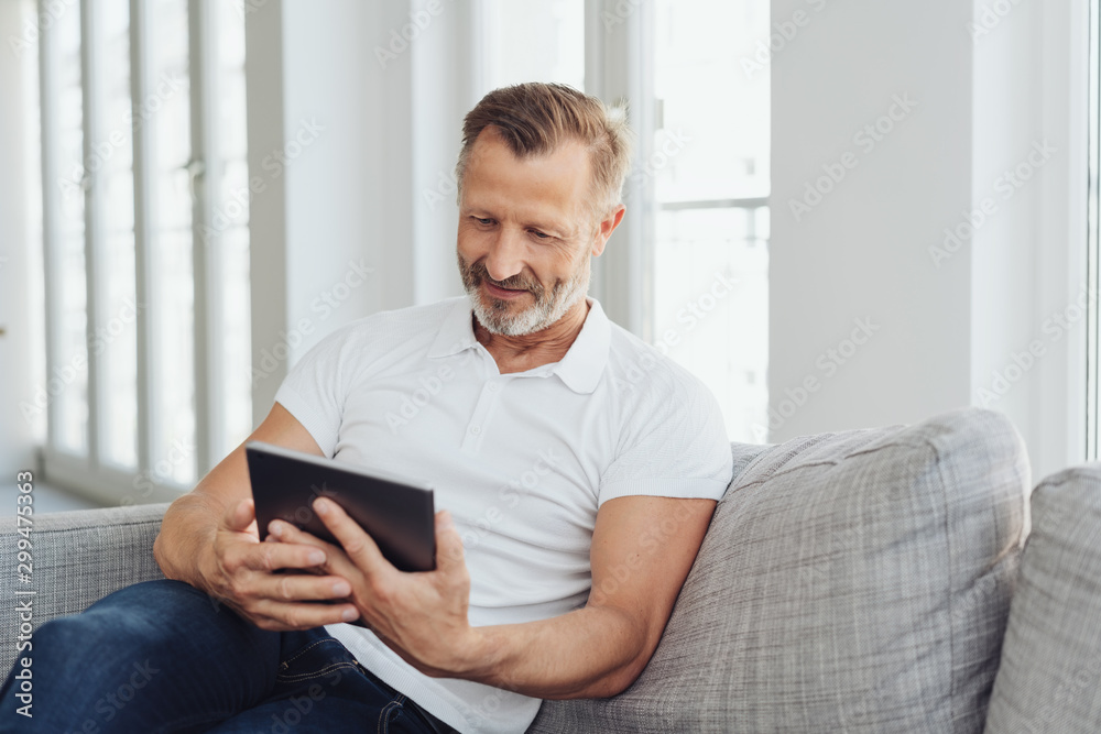 Man relaxing at home with his tablet pc - obrazy, fototapety, plakaty 
