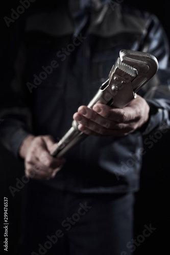 Professional construction worker shows a gas lever wrench on a dark background