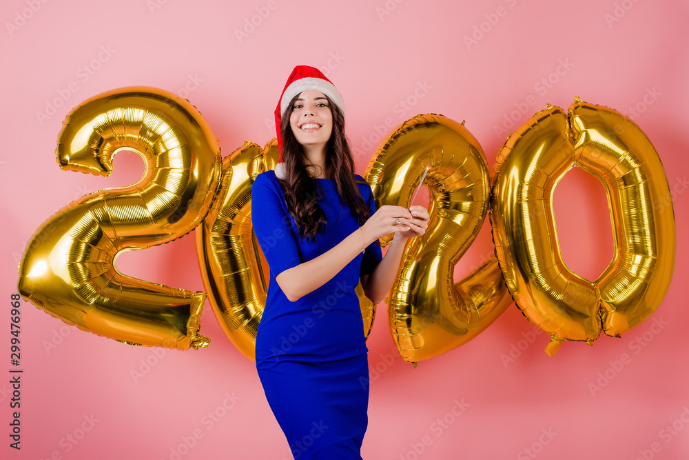 woman in santa hat in front of 2020 new year christmas balloons