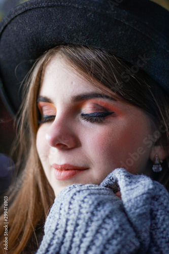 Stylish autumn girl in the center of the old town. Sweater, hat and leather jacket. Atmosphere. Makeup