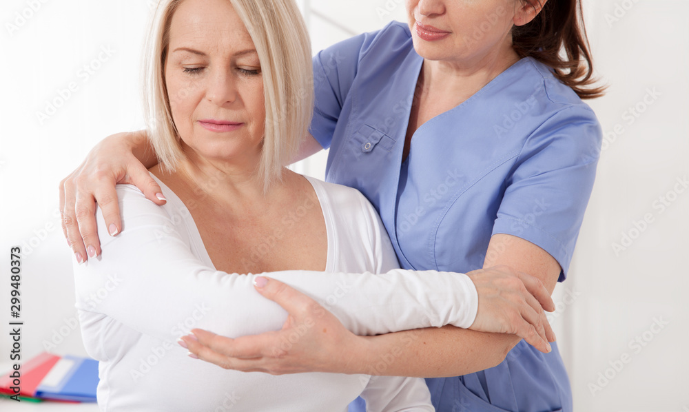 Fototapeta premium Physiotherapist working with middle aged patient in clinic