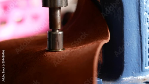 Female worker using press for installing metal eyelet on geniune leather product. Close up 4k photo