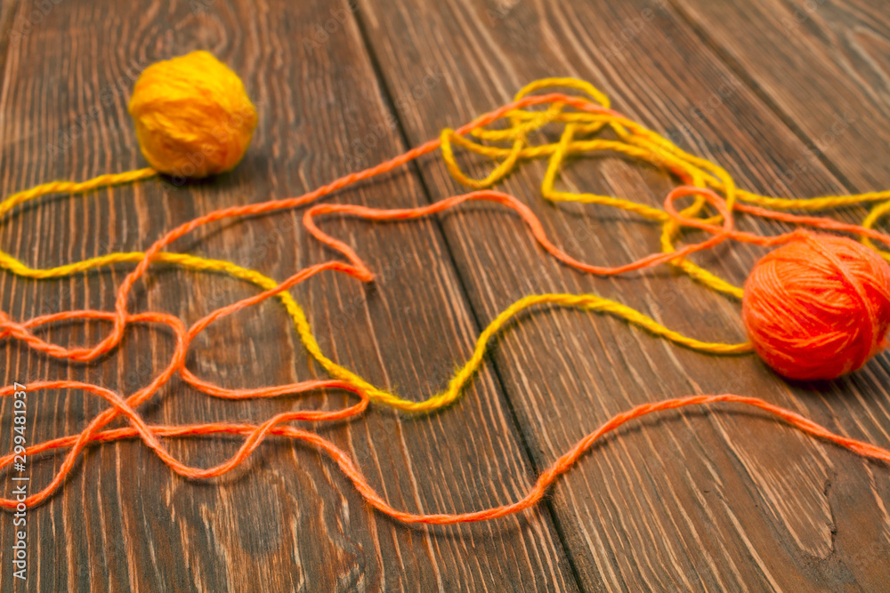 Yellow and orange balls of yarn on a wooden background Yellow and orange balls of yarn on a wooden background
