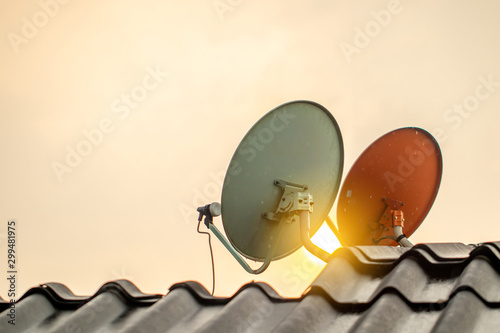 The satellite dishes on the roof for digital TV reciever with the sun light flare in the afternoon or evening. 