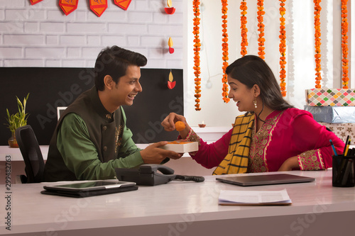 Man sharing sweets with his colleague on the occasion of Diwali.  	 photo