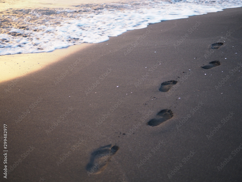 foot prints on a black sand beach with tilt-shift blur. Surf in background. Concept for loneliness, solitude, depression foot prints on a black sand beach with tilt-shift blur. Surf in background. Concept for loneliness, solitude, depression