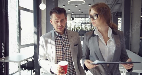 Businessman and lady assistant walking in office, female showing boss prepared report