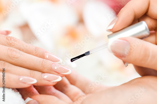 Bild auf Leinwand Beautician in luxury salon applying lacquer or varnish gel on nails