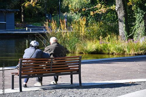 Old couple sitting on a park bench in the woods