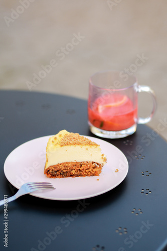  Classic simple New York cheesecake, closeup, selective focus Cheesecake on a summer playground on the table. Carrot sponge cake with cheese filling. Dessert in a cafe on the street with tea.