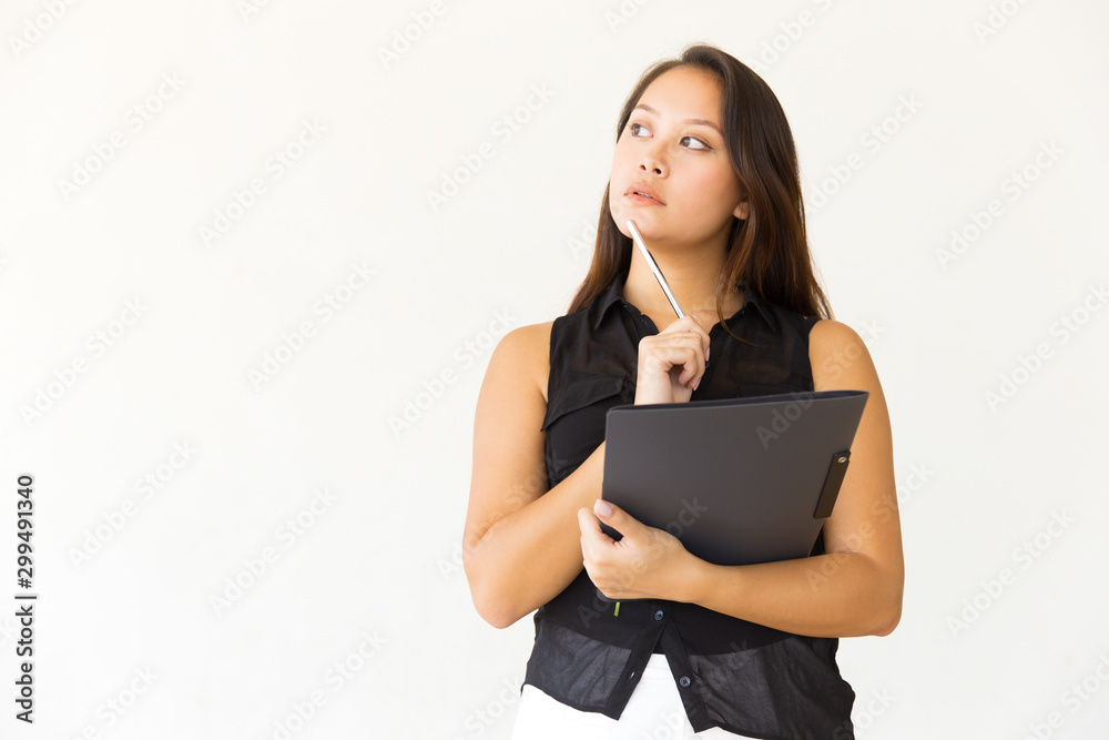 Pensive young woman with folder and pen. Thoughtful young female student holding folder with pencil and looking side on white background. Education concept Pensive young woman with folder and pen. Thoughtful young female student holding folder with pencil and looking side on white background. Education concept