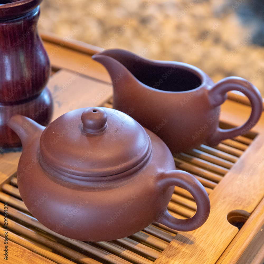 Japanese pot and milk pitcher on wooden table. Traditional tea drinking concept. Simple pottery top view on warm wood
