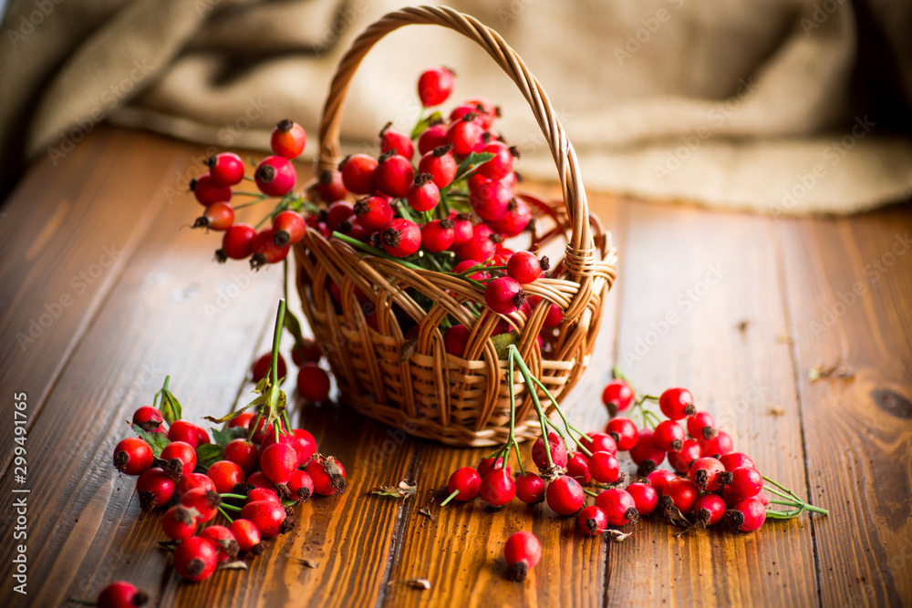 ripe red dogrose in a basket on a wooden - obrazy, fototapety, plakaty 
