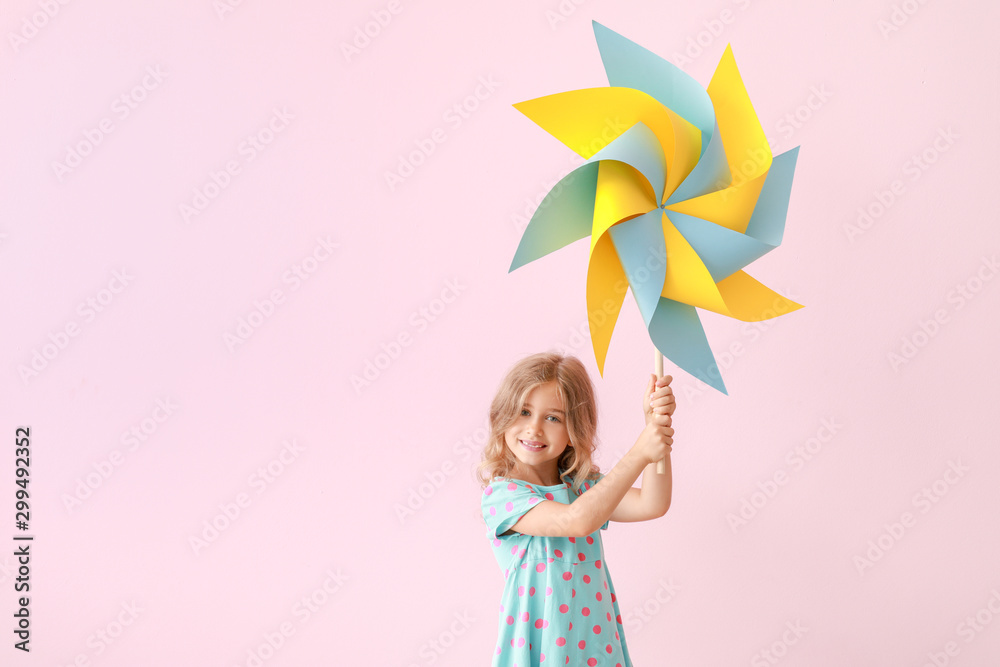 Cute little girl with paper windmill on color background Cute little girl with paper windmill on color background