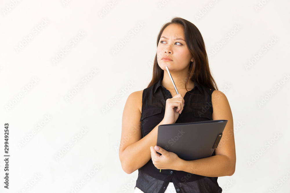 Thoughtful woman with folder and pen. Pensive young female student holding folder with pencil and looking side on white background. Education concept Thoughtful woman with folder and pen. Pensive young female student holding folder with pencil and looking side on white background. Education concept