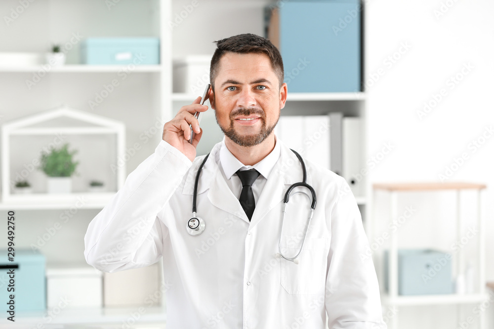 Portrait of male doctor talking by phone in clinic Portrait of male doctor talking by phone in clinic