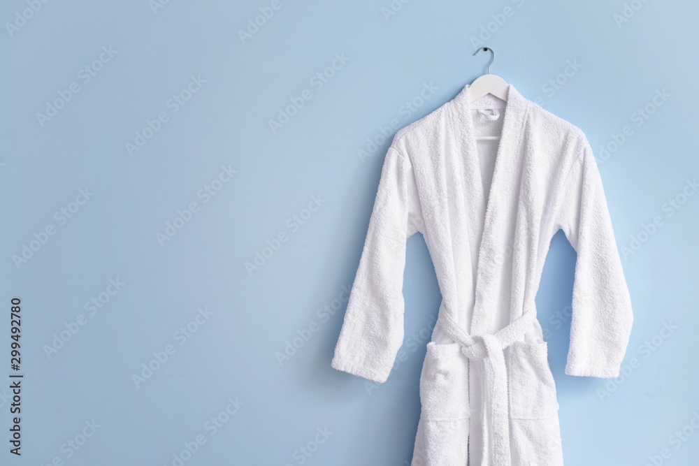 Clean bathrobe hanging on wall in room - obrazy, fototapety, plakaty 