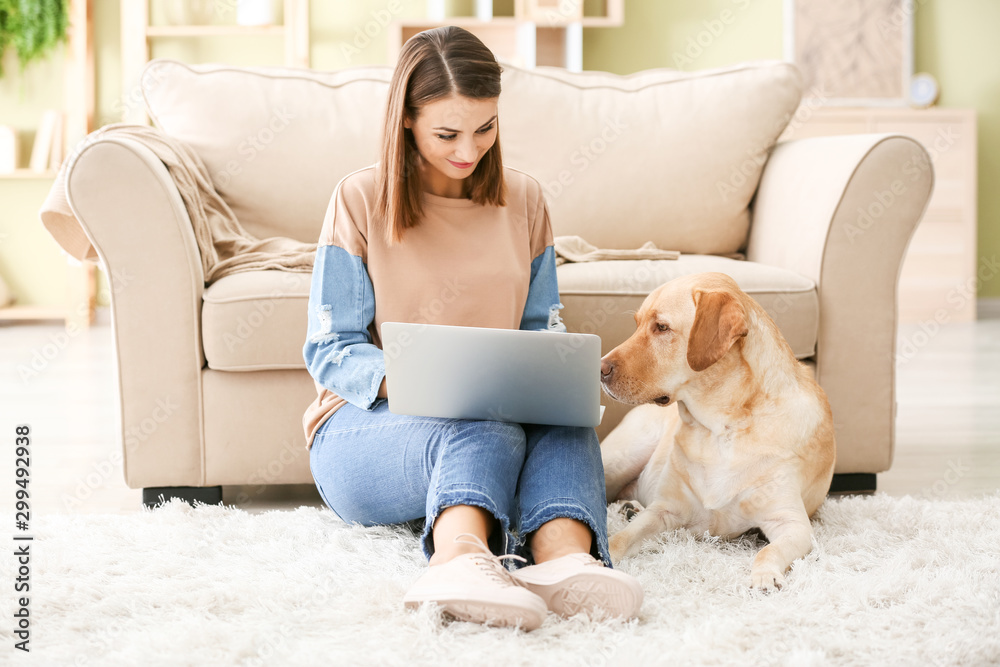 Beautiful young woman with cute dog using laptop at home Beautiful young woman with cute dog using laptop at home