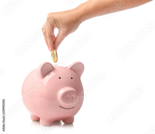 Female hand with coin and piggy bank on white background