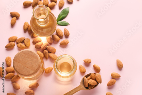 Composition with tasty almonds and oil on color background