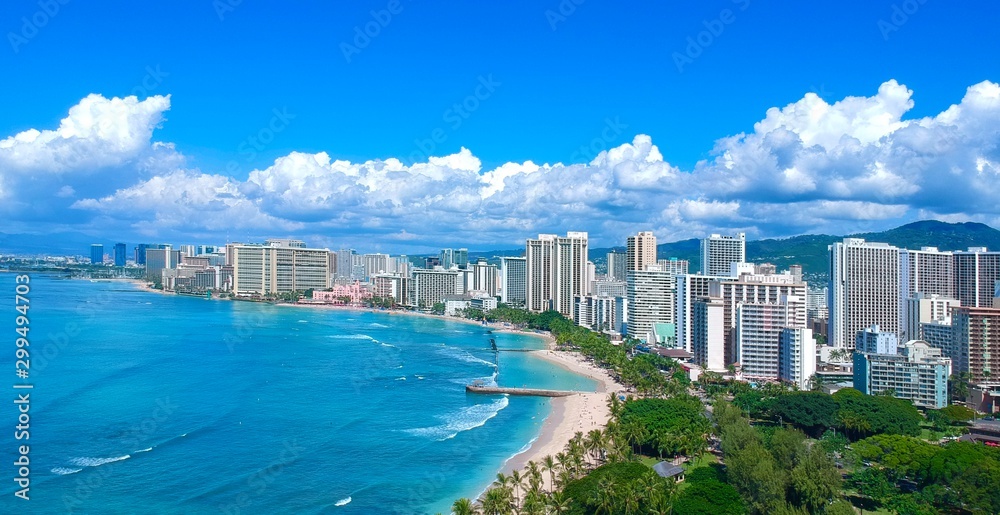 Panorama Aerial drone view of Waikiki beach Honolulu Hawaii USA white sandy beach turquoise blue waters lush green mountains and hotel resorts on the sea shore 