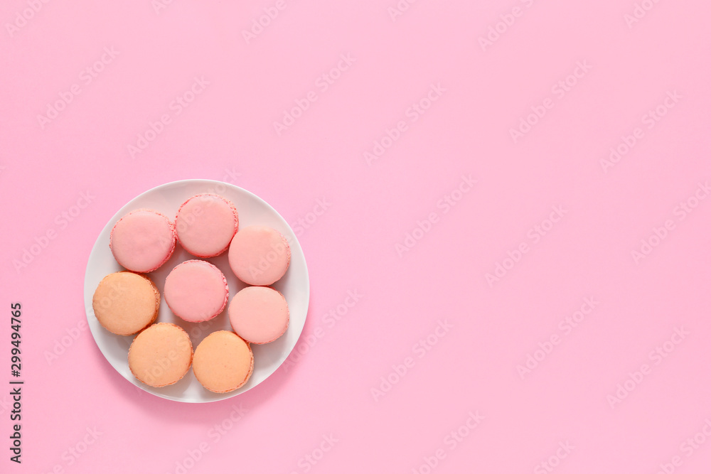 Plate with tasty macarons on color background