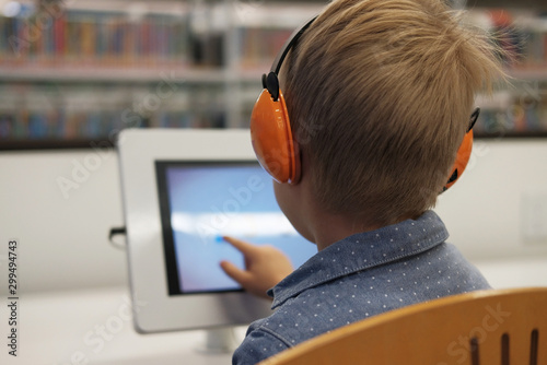 Wallpaper Mural Elementary school boy sitting in library, using touchscreen computer for education. Concept: technology and modern learning environment Torontodigital.ca