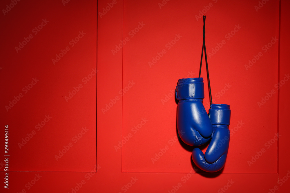 Fototapeta Pair of boxing gloves hanging on color wall