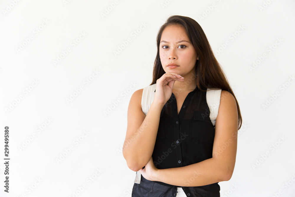 Focused pensive student girl posing in studio and looking at camera. Young Latin woman in casual standing isolated over white background, touching chin. Advertising concept Focused pensive student girl posing in studio and looking at camera. Young Latin woman in casual standing isolated over white background, touching chin. Advertising concept