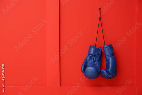 Pair of boxing gloves hanging on color wall © Pixel-Shot