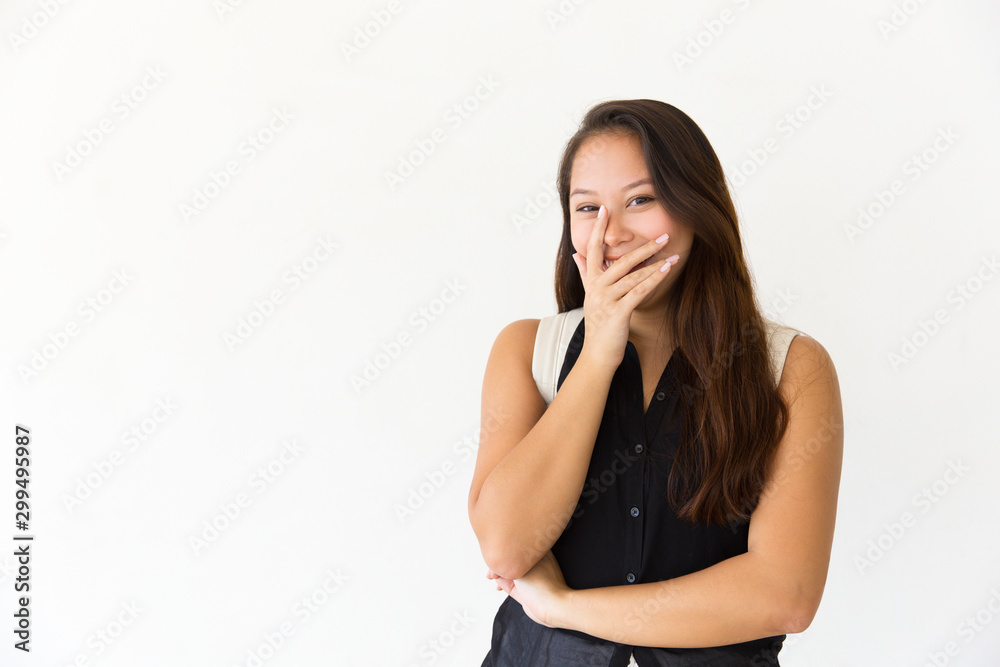 Joyful girl covering mouth with hand and laughing. Young Latin woman in casual standing isolated over white background. Having fun concept Joyful girl covering mouth with hand and laughing. Young Latin woman in casual standing isolated over white background. Having fun concept