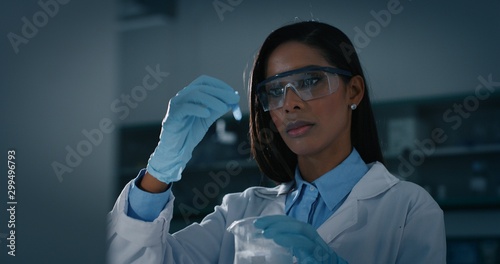 Portrait of dark skin female scientist is analyzing a liquid to extract the DNA and molecules in the test tubes in laboratory.  photo