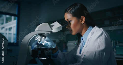 Close up of dark skin female scientist is analyzing a sample to extract the DNA and molecules with microscope in laboratory.