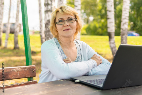 A woman with a laptop looks at a document in a cafe, office