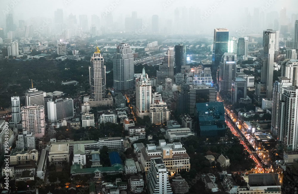 Obraz premium Top view of the streets of Bangkok's business district in the evening in foggy weather. Skyscrapers in the fog. Traffic jam on the street in the business district of Bangkok, Thailand.
