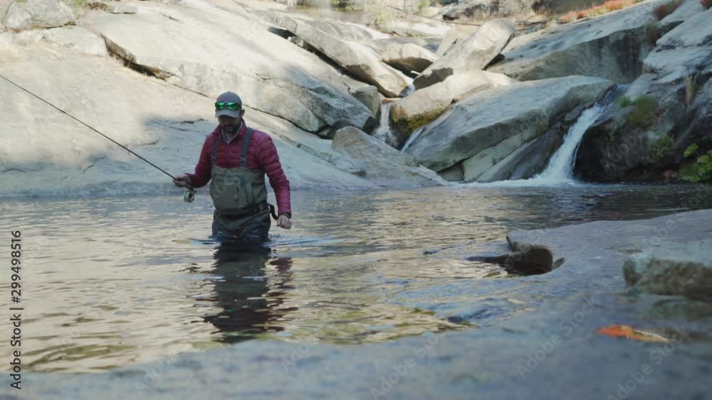 Static Shot Of Caucasian Man Coming Out Of River After Fly Fishing Static Shot Of Caucasian Man Coming Out Of River After Fly Fishing