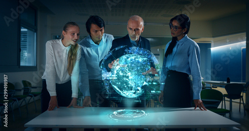 Obraz na płótnie A group of designer are using a futuristic sophisticated technology screen with augmented reality holograms for a new worldwide global project realization in an office