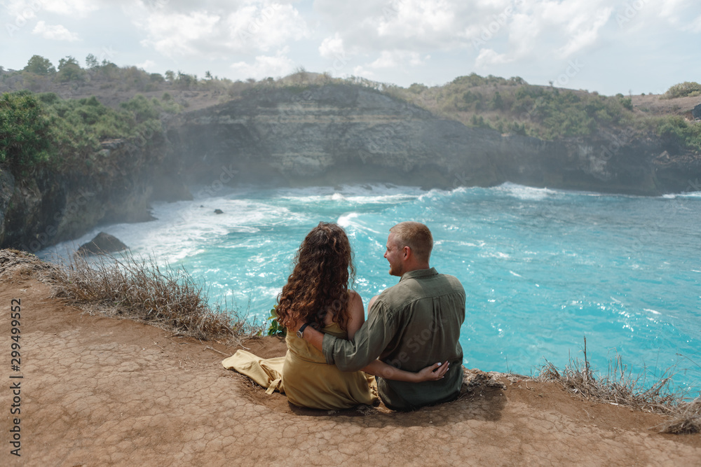 Young couple appreciating the view at Broken Beach on Nusa Penida Island in Indonesia. Amazing landscape and crystal clear water.